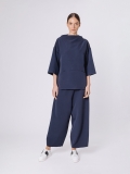 Vista frontale della t-shirt in tessuto di neoprene ultralight, modello dalla linea diritta con collo a cratere e maniche a kimono, lunghe al gomito. Impuntura trasversale all'interno della quale si trovano due tasche nascoste.
Lunghezza ai fianchi, con