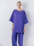 Vista frontale della maxi blusa in tessuto di neoprene ultralight con scollo rotondo a barchetta, e maniche a kimono lunghe al gomito. Corpo molto ampio. Lunghezza asimmetrica con spacchi laterali.