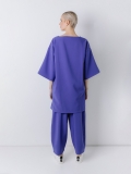 Vista posteriore della maxi blusa in tessuto di neoprene ultralight con scollo rotondo a barchetta, e maniche a kimono lunghe al gomito. Corpo molto ampio. Lunghezza asimmetrica con spacchi laterali.