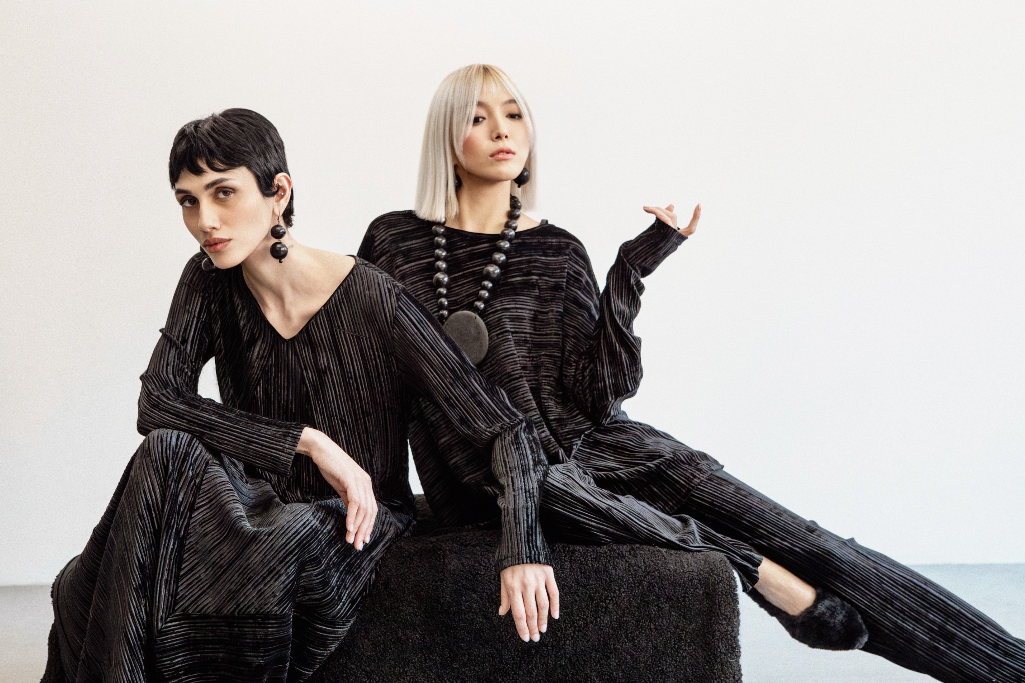 Two models in dark pleated suits